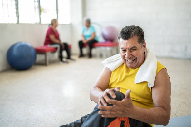 пожилой мужчина чувствует боль в колене в студии йоги - mexico only men senior men mature men стоковые фото и изображения