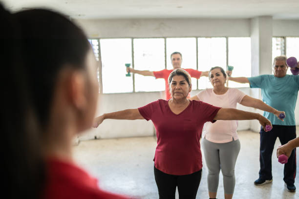 istock Fitness instructor with senior class lifting weights at the gym 1435831423