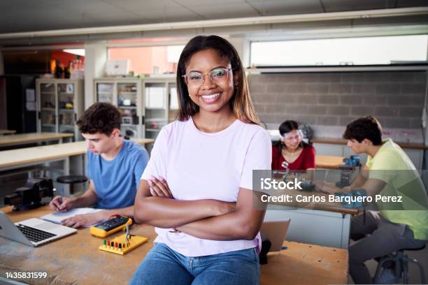 Portrait Of A Latina In The Classroom Looking At The Camera With Her Arms Crossed Young Students Doing Technical Vocational Practice In Electronic Class Concept Of Education And Technology Stock Photo - Download Image Now