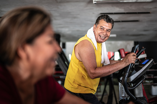 Senior man exercising on a treadmill with gym partner at the gym
