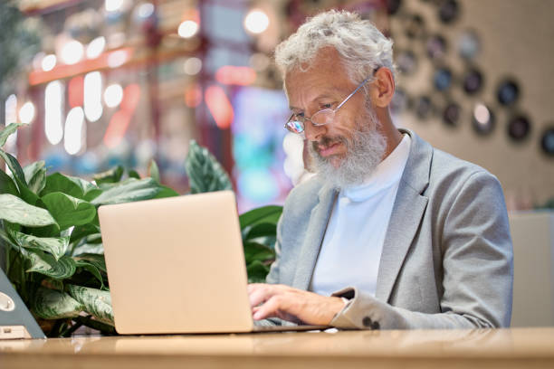 istock Busy older senior business man using laptop working late on computer. 1435831806