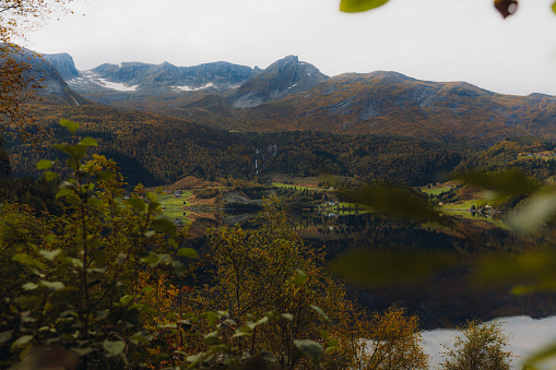 Dramatic view of the reflection ford with vire of the tiny village and thr snowcapped mountains during autumn time in Western Norway