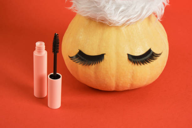 istock mascara in pink packaging mock up and pumpkin in santa hat and false eyelashes on red background 1435833100