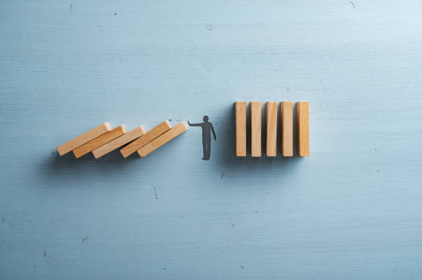 istock Silhouette of a man making a stop gesture stopping collapsing dominos 1435833157