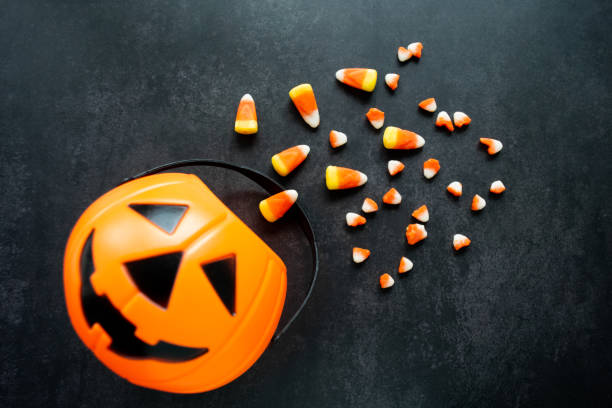 istock Plastic pumpkin basket, candy corn. Some are broken, look like small teeth. Halloween harmful sweets 1435833258