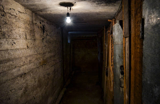 istock A scary dark concrete corridor in the basement, lit by a single light bulb. Copy space 1435833627