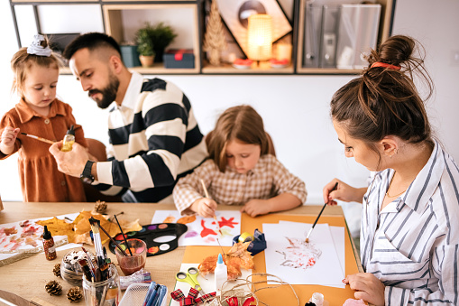 Young beautiful family with two children drawing at home