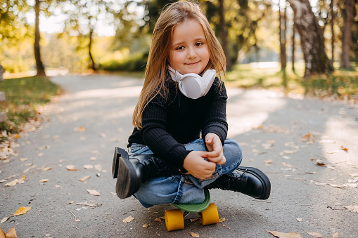 Little girl is sitting on a skate in the park
