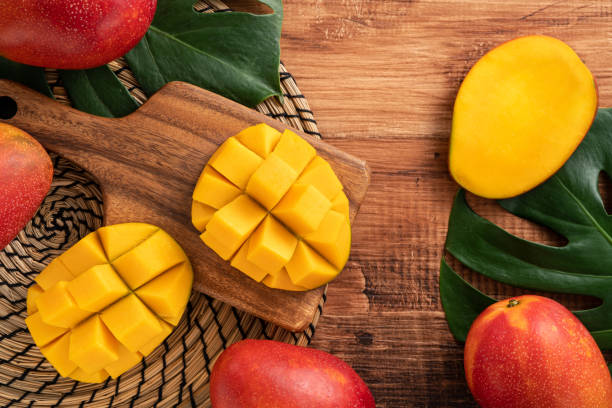 istock Fresh mango fruit with leaves over dark wooden table background. 1435857977