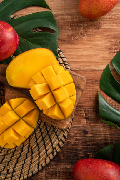 istock Fresh mango fruit with leaves over dark wooden table background. 1435857985
