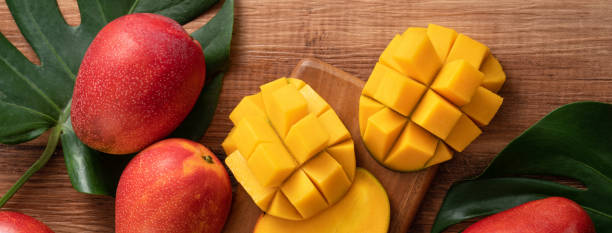 istock Fresh mango fruit with leaves over dark wooden table background. 1435858061
