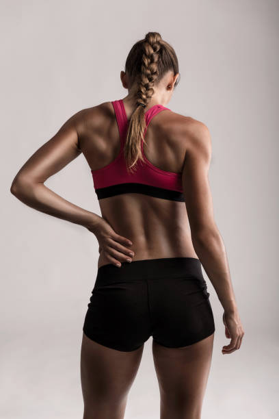 Feeling pain it my backs Studio shot of a sporty young woman holding her lower back in pain muscle and bone aches stock pictures, royalty-free photos & images