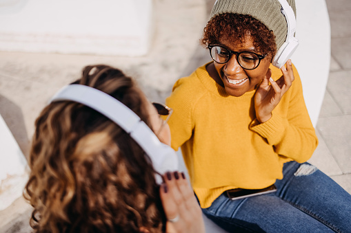 Women sit in the park and listen to their favorite music on headphones