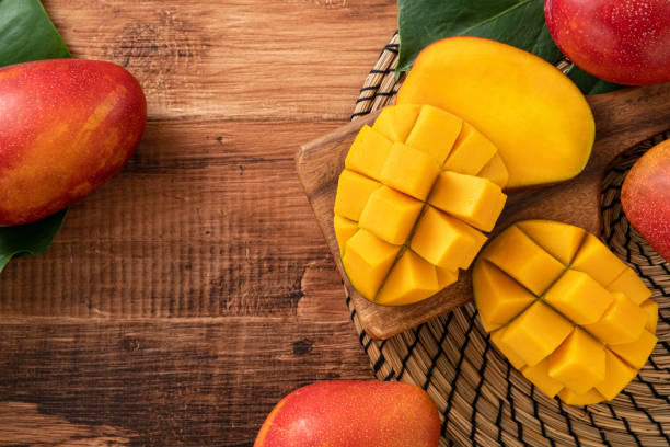 istock Fresh mango fruit with leaves over dark wooden table background. 1435861624