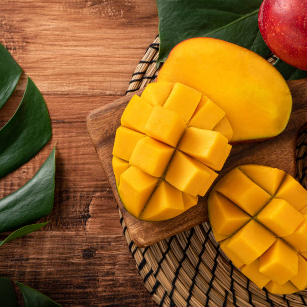 istock Fresh mango fruit with leaves over dark wooden table background. 1435861631