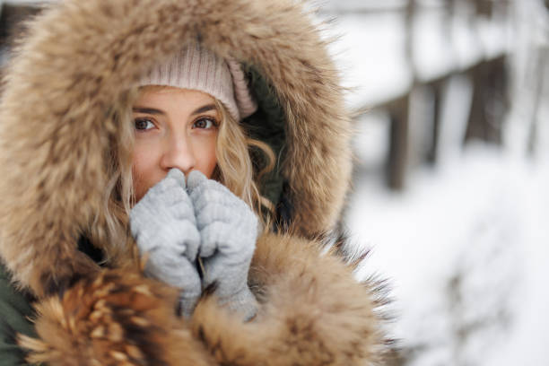 istock Young woman warming up her hands in winter forest 1435862218