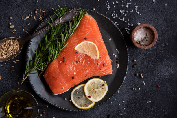 istock Uncooked raw salmon fish with herbs on dark background 1435867182