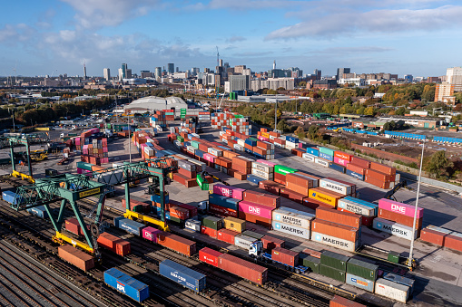 Birmingham, UK - October 17, 2022.  An aerial view of the Freightliner Rail Terminal at Landor Street in Birmingham with shipping containers loading onto freight trains and cityscape skyline
