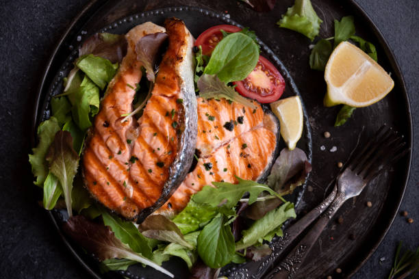 istock Cooked salmon fish with vegetables on dark background 1435872727