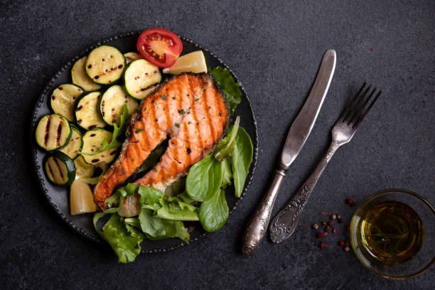 istock Cooked salmon fish with vegetables on dark background 1435872783