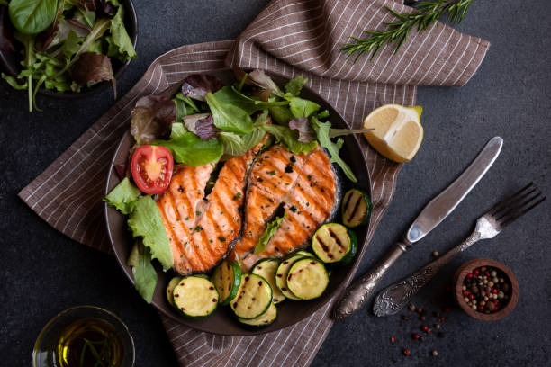 istock Cooked salmon fish with vegetables on dark background 1435872830