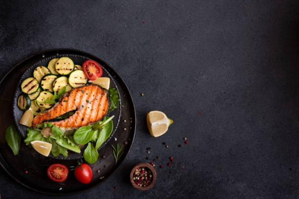 istock Cooked salmon fish with vegetables on dark background 1435873120