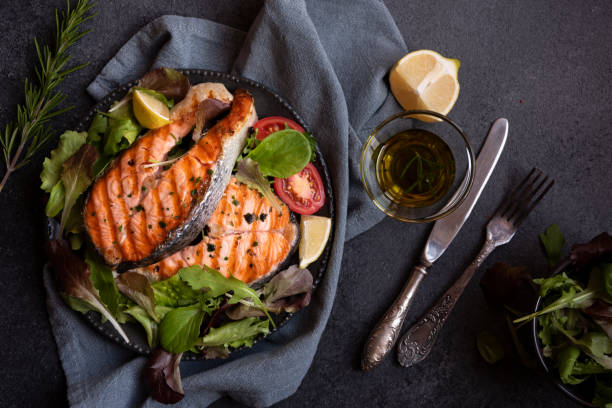 istock Cooked salmon fish with vegetables on dark background 1435873413