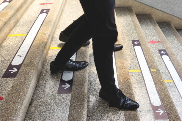 istock businessman legs walking down the stairs 1435875261