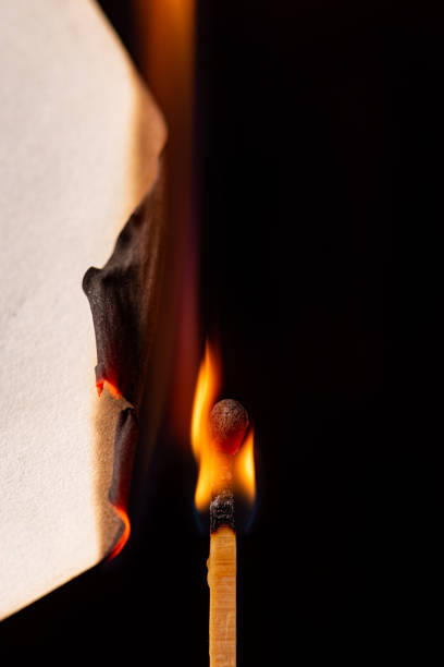 cerilla y pedazo de papel quemándose en detalle visto a través de una lente macro, fondo negro, enfoque selectivo. - paper match fotografías e imágenes de stock
