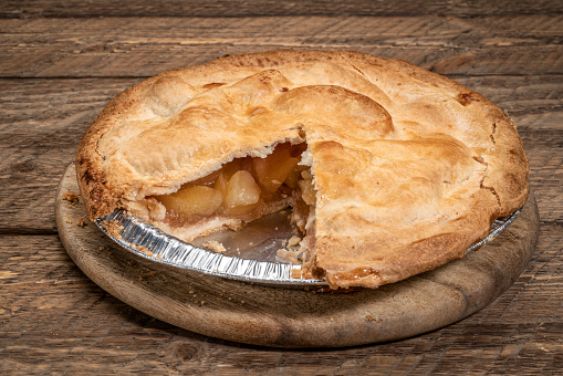 freshly baked apple pie on in an aluminum tray with piece taken