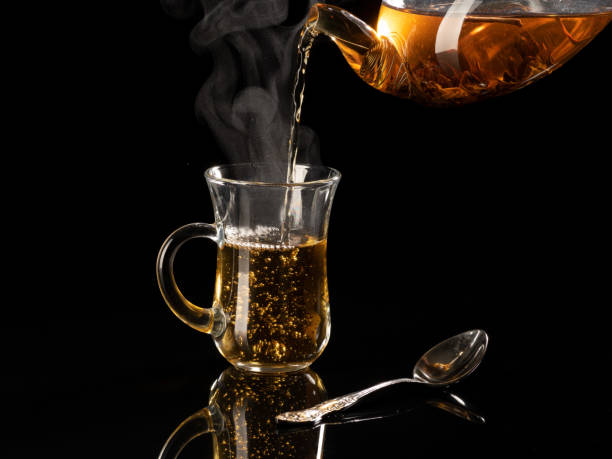 istock Hot tea pours into a transparent mug on a black background 1435887709