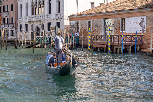 Venice, Italy - October 8th 2022: Large group of people being ferried over Canal Grande in a gondola with two gondoliers