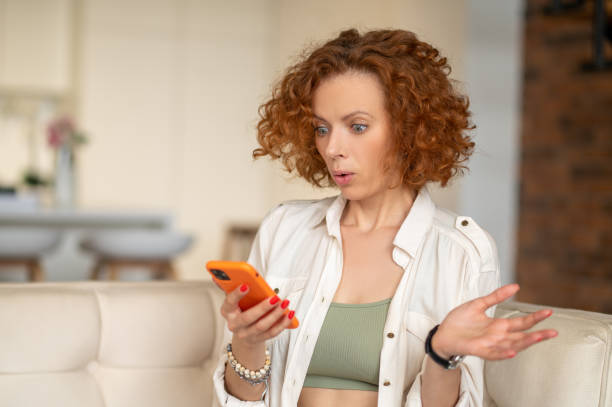 istock Cute ginger woman with a smartphone in hands 1435889996