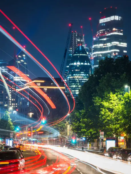 Photo of London traffic zooming through busy night streets below City skyscrapers