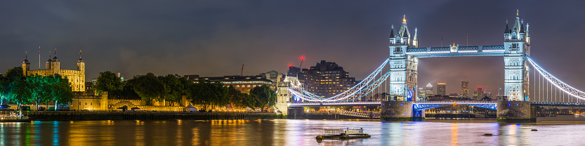 River Thames overlooked by Tower Bridge illuminated at night in the heart of London, UK.