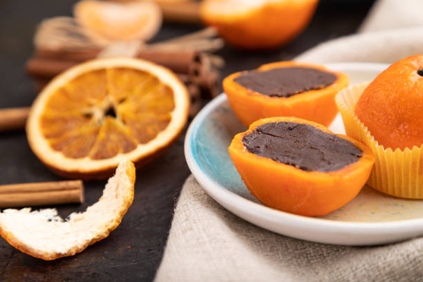 Truffle chocolate tangerine candies on a black concrete background and linen textile. Side view, close up, selective focus.