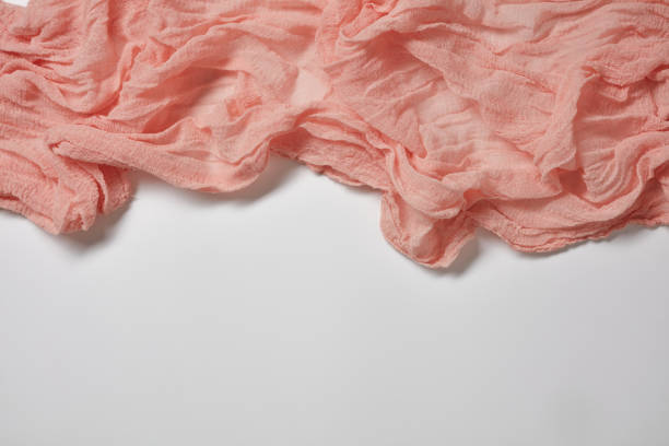 Folded cotton gauze fabric on a white background. Crinkle pink gauze fabric. Dyed gauze fabric