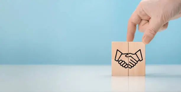 Photo of Business contract. Hand putting hand shaking which print screen on wooden cube block for business deal and agreement concept. Agreement, partnership or deal concept. copy space