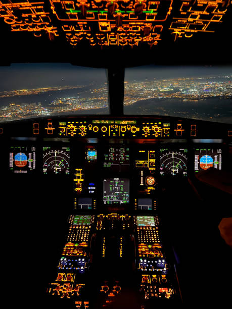 le panneau de contrôle du point de vue du cockpit de l’avion la nuit et les lumières de la ville sont vus à partir de la fenêtre photo horizontale - cockpit airplane aerospace industry control photos et images de collection
