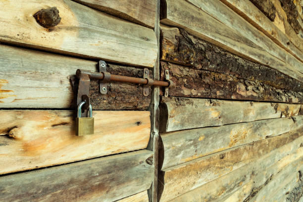 Wooden door closed with rusty lock and padlock. Surface of rustic wooden strips in perspective. Country building style.