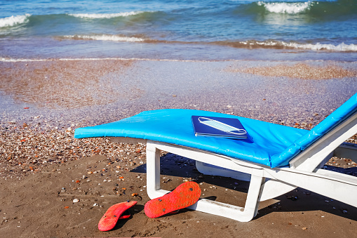 Summer vacation destination, work or study online beach,  laptop and face mask lie on sun lounger with sea in the background. Vacation And Tourism  Concept. sunbeds