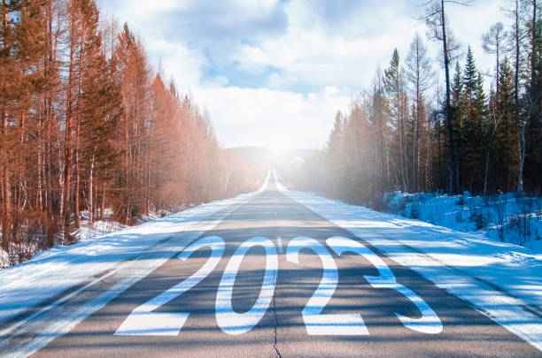 das wort 2023 steht auf einer autobahn inmitten einer leeren asphaltstraße im morgengrauen und einem schönen blauen himmel.  neues jahr 2023 konzept. konzept der planung und herausforderung, geschäftsstrategie, neue lebensveränderung - neujahrsvorsatz stock-fotos und bilder