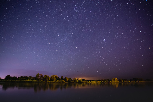 Stars on night sky. Beautiful night landscape. Long exposure. Summer starry sky. Milky Way. River. Water