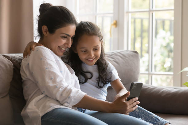 istock Cute little girl and mom using modern smart phone 1435908306