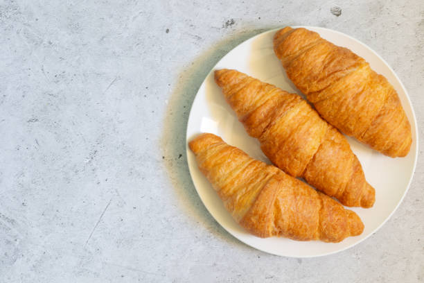 istock Croissants on white plate on light concrete background, top view with copy space 1435909521