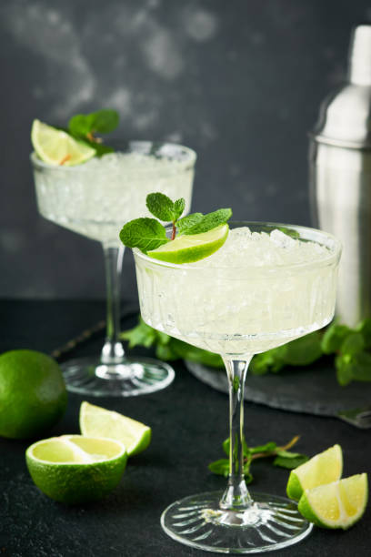 istock Margarita cocktail with lime, tequila, mint and ice on dark table with amazing backlight, copy space. Classic Margarita or Daiquiry Cocktail. Bar card or counter concept. Selective or soft focus. 1435910411