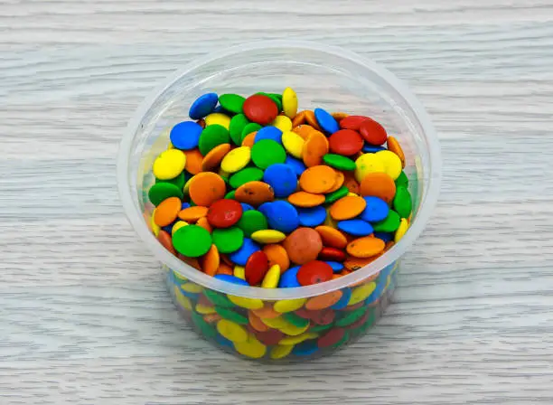 Photo of Assorted colorful bunties served in disposable cup side view of indian and pakistani dessert