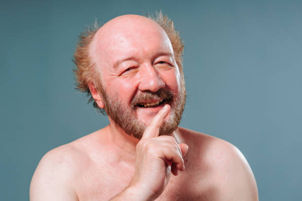istock Front view man aged isolated studio looks into the camera slyly smiles smirks index finger exposed. 1435914258