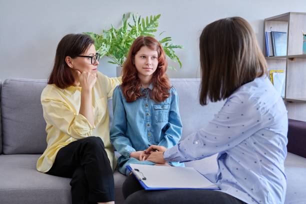 Child psychologist session, mother daughter therapist together in office stock photo