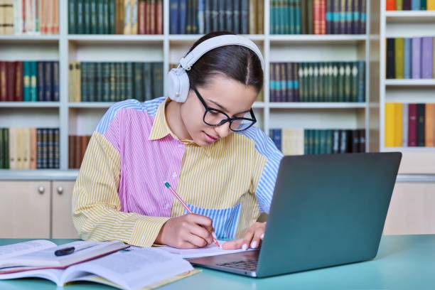 istock Teenage girl student studying in library, using laptop 1435917350